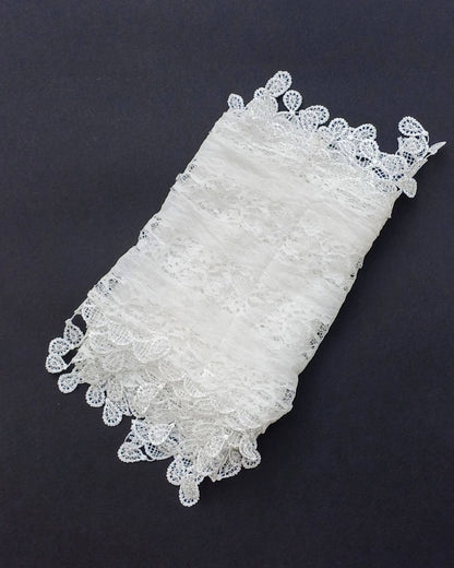 Aurora's Array: A delicate white lace scarf, folded to show its intricate floral pattern and scalloped edges.