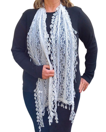 Aurora's Array: Woman models a delicate white lace scarf with an intricate floral pattern and scalloped edges.