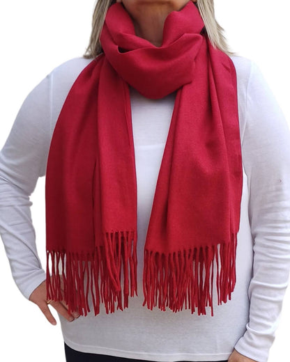 Aurora's Array: Woman models a soft, warm  wine red, crimson wool blend scarf with fringed edges, draped around her neck and shoulders.