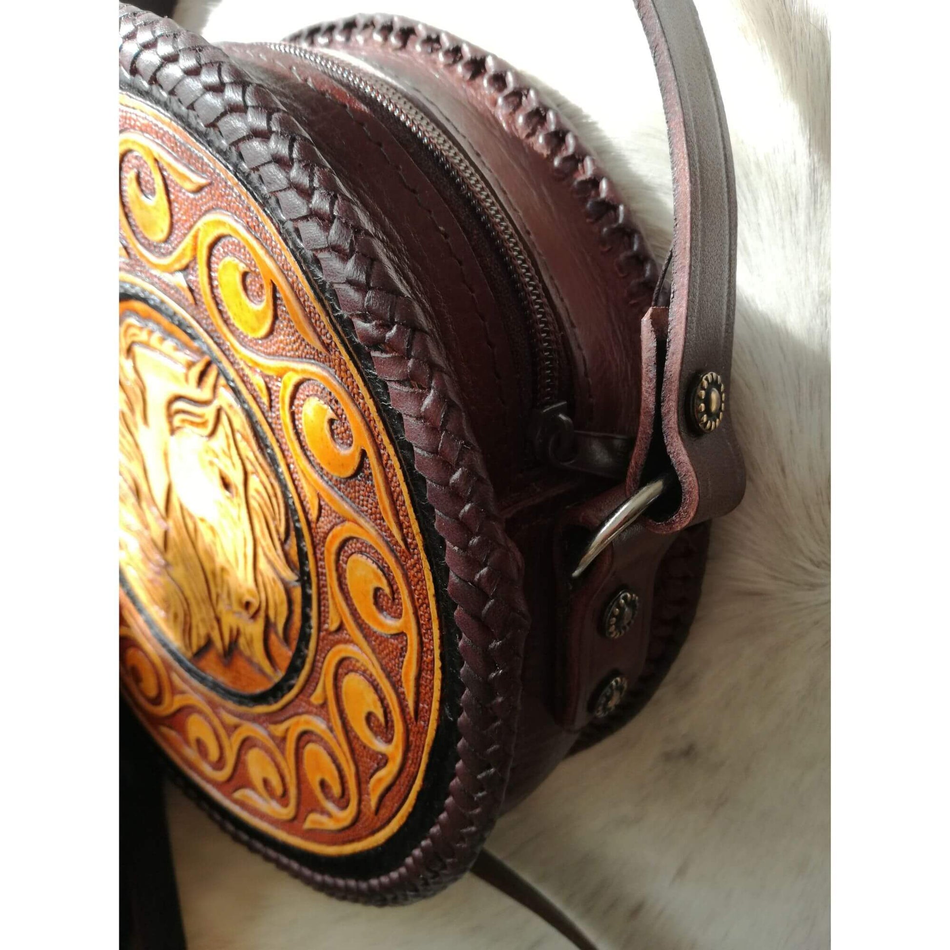 Side view of zip closure and adjustable strap on horse-themed leather bag