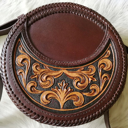 Front-facing image of hand-tooled leather crossbody bag with ornate floral pattern