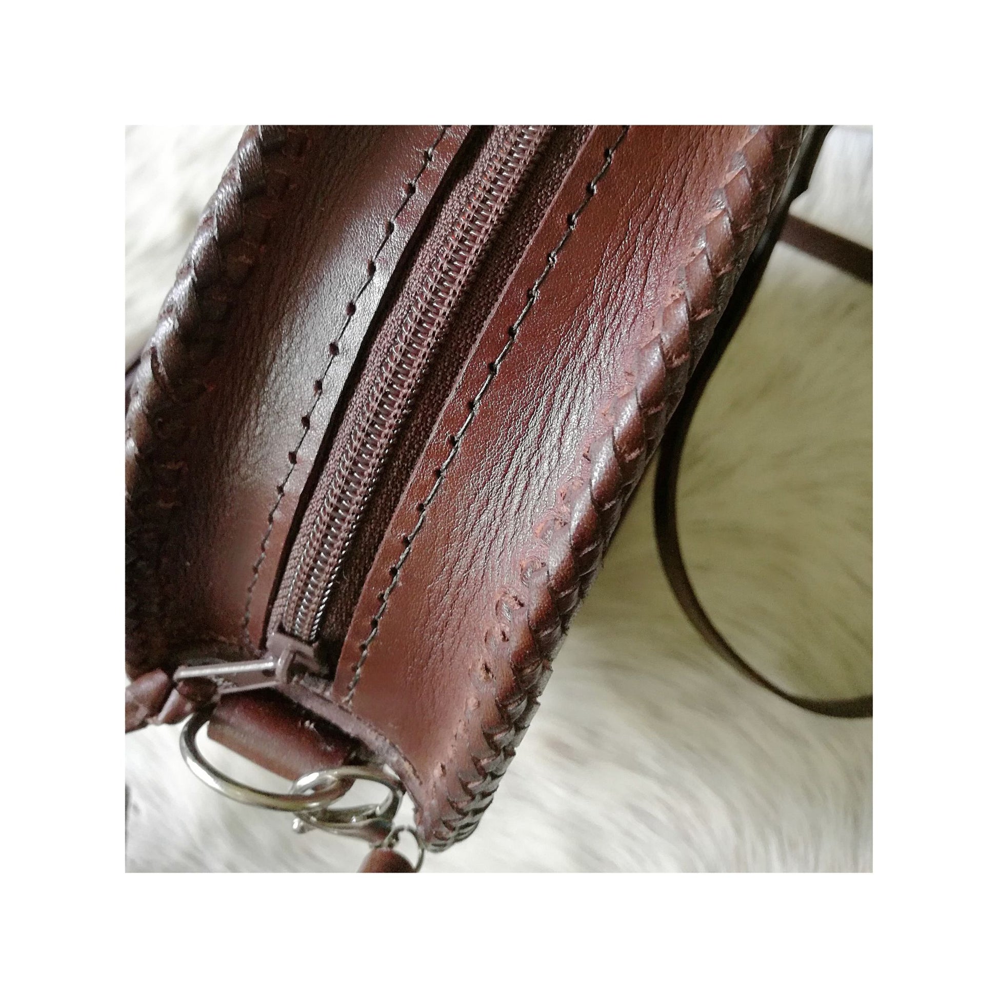 Top view of brown leather crossbody bag showing zip closure and hand stitching