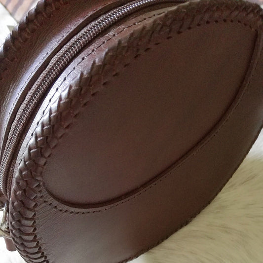 Back view of handmade round leather bag with smooth finish and laced edges