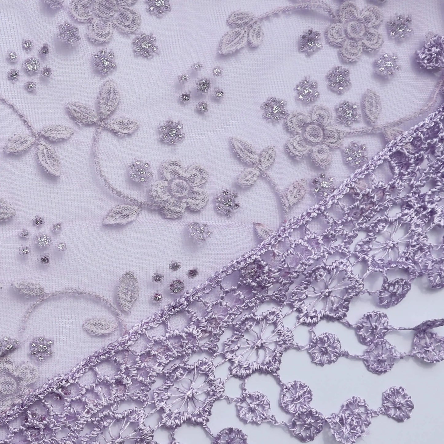 Close up of the Auroras Array Glitter Triangle Scarf in lilac showing floral lace embroidery and glitter detail on sheer fabric