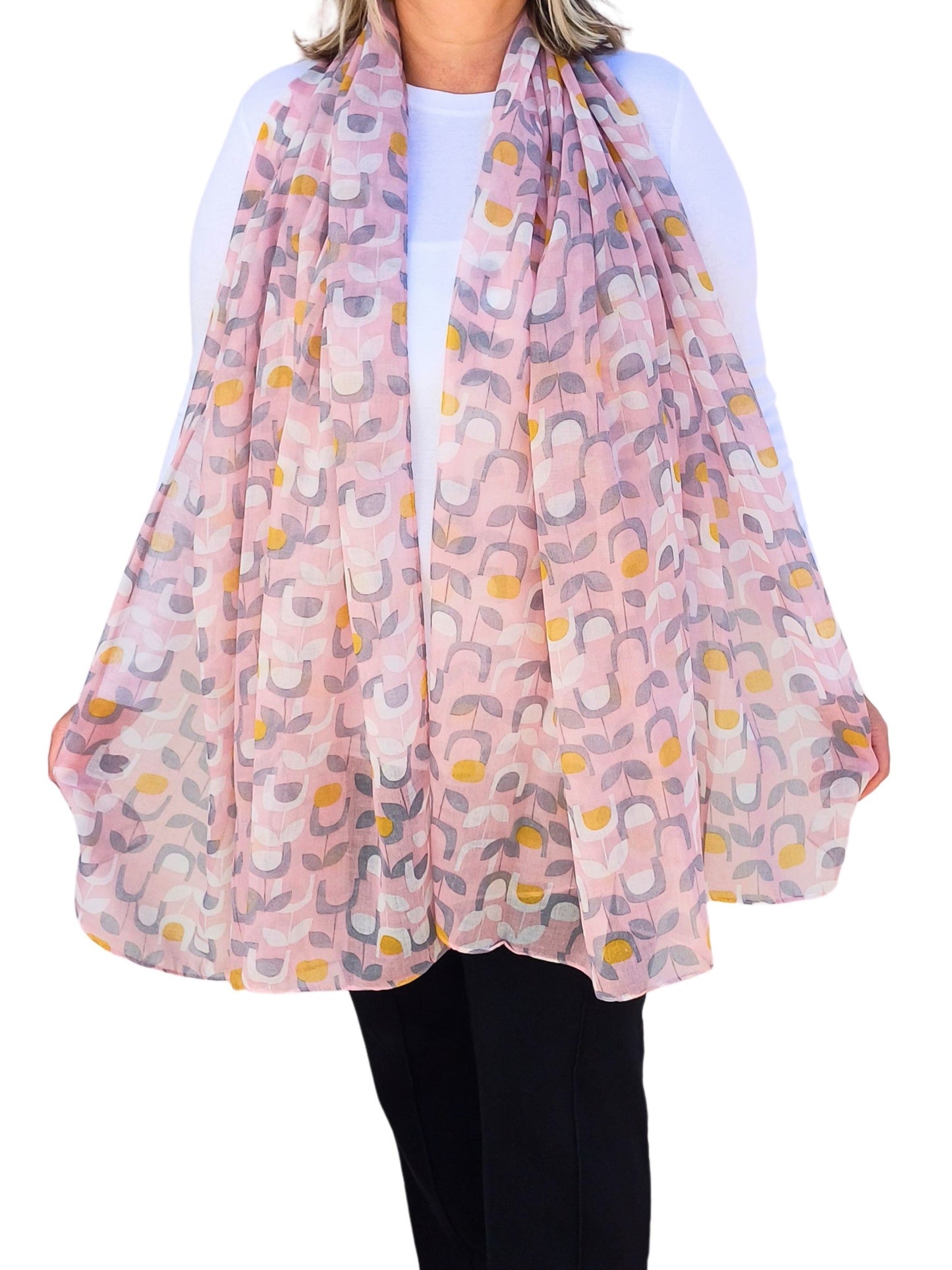 Aurora's Array:  Woman models a soft, lightweight oversized scarf with a retro floral print in shades of pink, grey, white, and yellow.