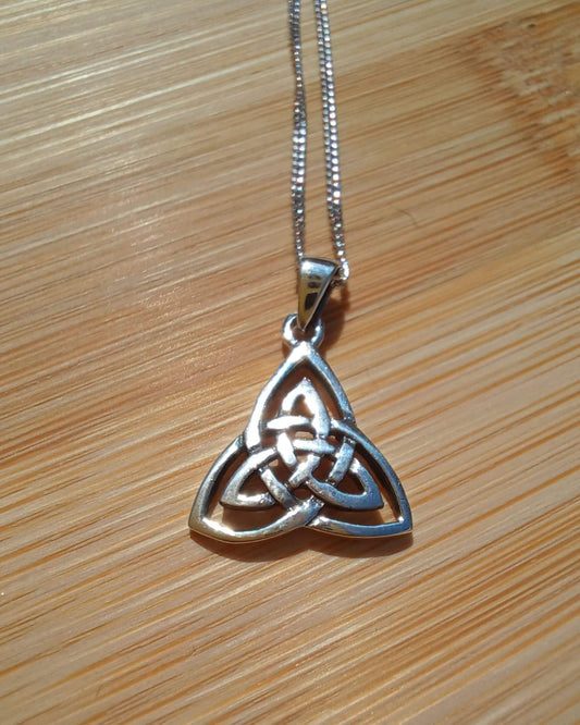 Sterling silver Celtic triangle pendant with trinity knot design on wooden background