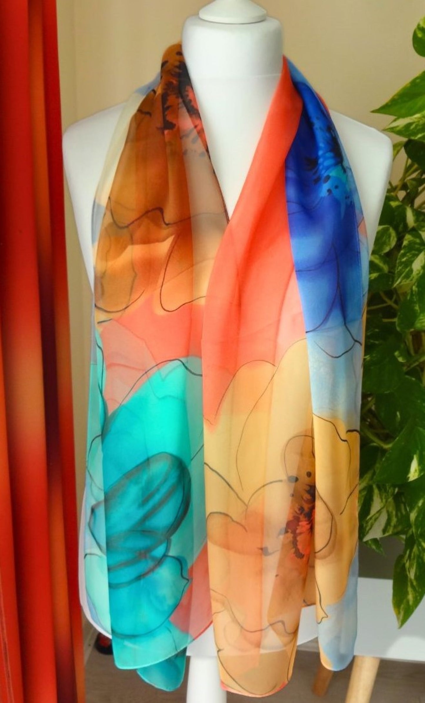Light chiffon scarf with bold multicoloured floral pattern in coral, blue and gold displayed on mannequin