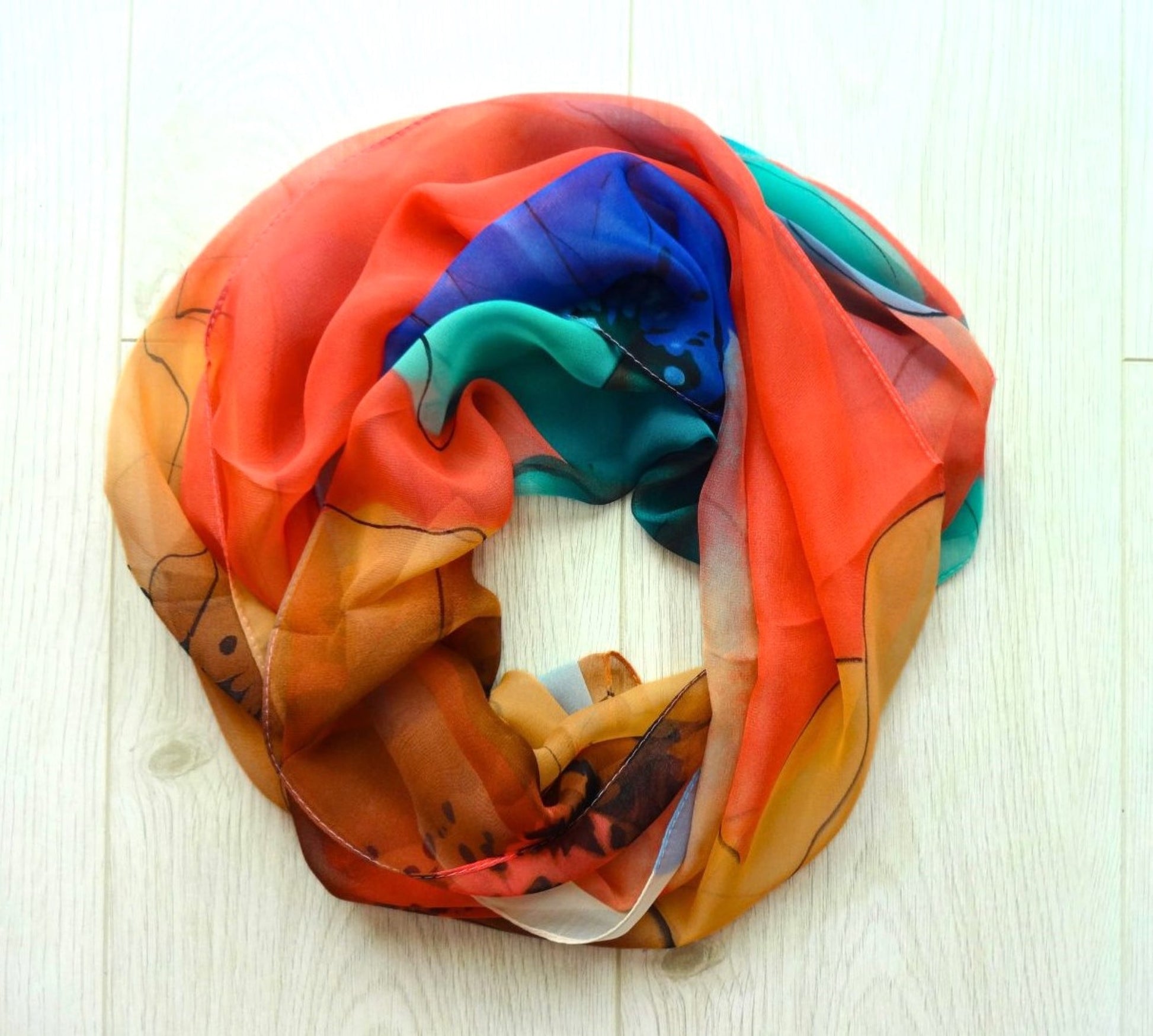 Light chiffon scarf with colourful abstract flower pattern in orange, blue and teal arranged in a circle