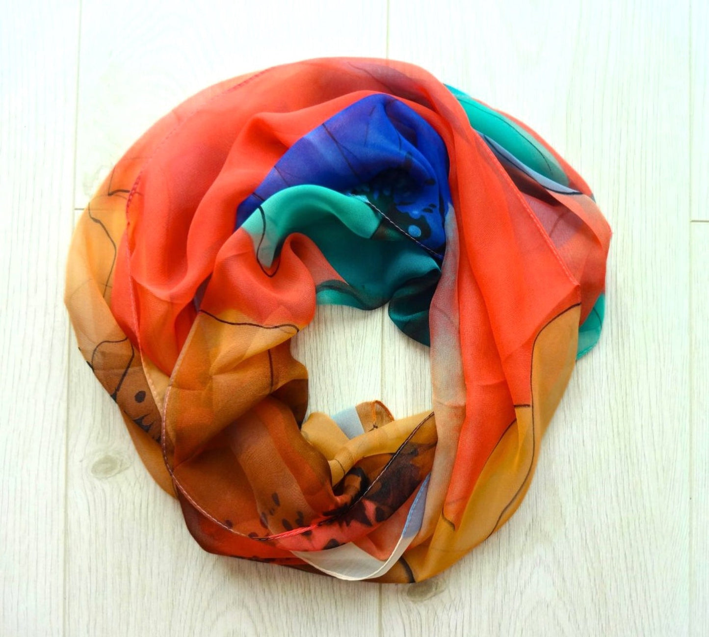 Light chiffon scarf with colourful abstract flower pattern in orange, blue and teal arranged in a circle