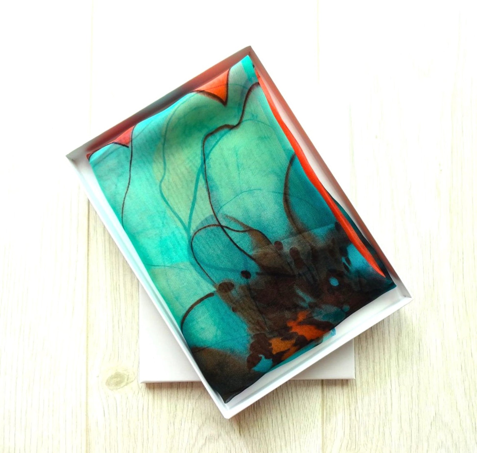 Lightweight chiffon scarf with teal and coral floral design neatly presented in a white gift box