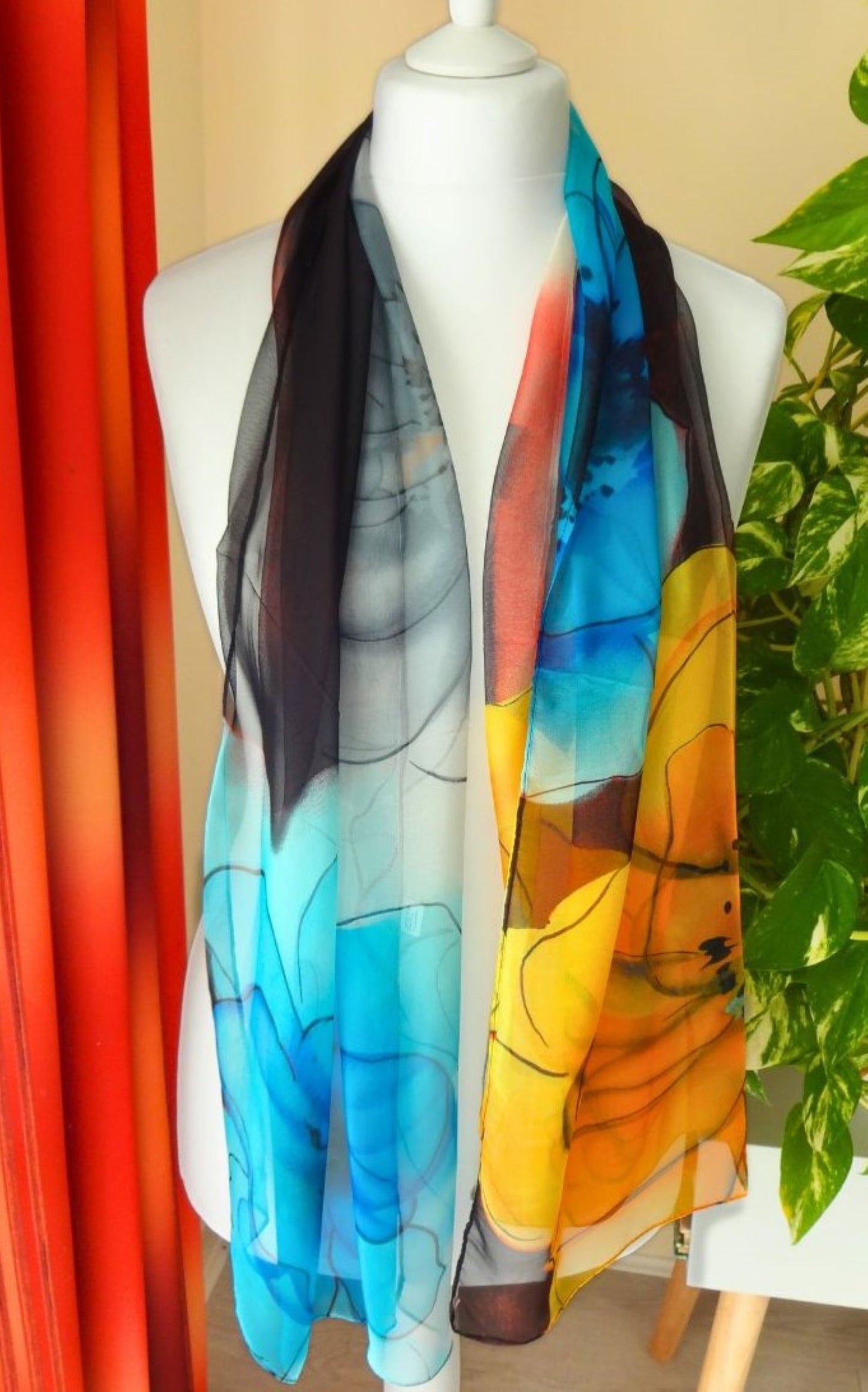 Lightweight chiffon scarf with bold floral pattern in turquoise, yellow and coral tones draped on mannequin