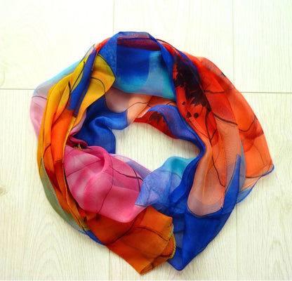 Sheer chiffon scarf with vibrant flower design in blue, red and orange arranged in a circle