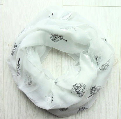 White scarf with silver foil tree of life patterns on a light wooden surface placed in a circle